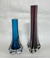 Two Whitefriars art glass vases side by side, showing full height and shape, one blue with lobed base and one amethyst with faceted base.