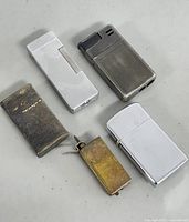 Image showing all five vintage collectible lighters arranged on a grey surface.