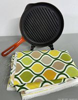 9-inch cast iron skillet with orange handle displayed with folded retro geometric fabric panel