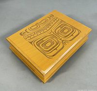 Top view of closed wooden jewelry box showing detailed carved Haida artwork on the lid depicting abstract, traditional Indigenous designs.