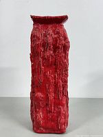 Front view of tall square red ceramic vase with textured vertical ridges and flared top.