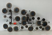 Front view of the metal wall sculpture showing the entire galaxy design with circular discs and chrome spheres.