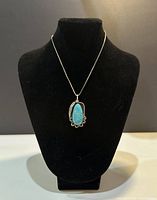Front view of the turquoise pendant necklace displayed on black bust, showing the turquoise stone and silver setting.