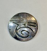 Front view of round vintage silver brooch with abstract design and texture.