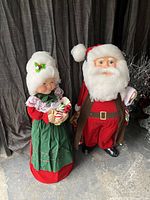 Full view of Santa and Mrs. Claus figures standing against a dark curtain backdrop, showing size and proportions.