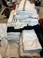 Assorted white and off-white cotton towels stacked and folded with various sizes and striped textures visible.