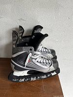 Side view of one skate showing black synthetic material with white and silver graphic details and heavily used condition.