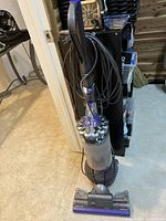 Assembled upright vacuum showing body, handle, cord wrapped around hooks, and ball steering mechanism