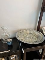 Photo showing the clear swirl patterned glass serving platter with chrome base alongside the blue teacup and clear glass pitcher