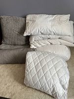Full view of king size comforter set including comforter, pillows, and mattress cover arranged on floor showing grey color and chevron pattern on comforter.