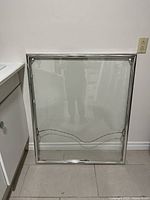 Chrome frame leaning against a wall, dimensions approximately 3x2.5 inches, metallic finish, used condition.