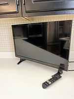 Front angle of the Insignia 39 inch LCD TV on white surface, remote control placed beside it.