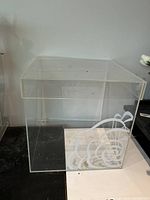 Clear acrylic square box with abstract white design on one side, minor surface marks visible