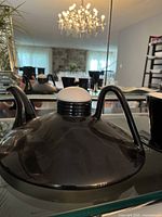 Close-up image of glossy black ceramic teapot with a curved handle and a removable lid, showing smooth reflective surface and modern design.
