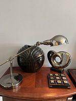 Photo showing the silver desk lamp with adjustable arm on a wooden surface alongside decorative items.