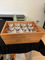 Shot glasses in wooden Corona box on black cloth