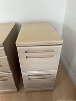 Front angled view of light wood 2-drawer filing cabinet with integrated handles.