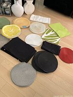 Placemats spread on floor showing various round and rectangular placemats in multiple colors and patterns including lemon slice and leafy designs
