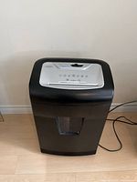 Front view of black Staples shredder placed on floor with power cord visible