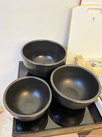 Set of three black ceramic bowls, varying sizes with smooth matte finish.