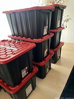 Eight black and red Tuff Store storage bins stacked in two columns indoors.