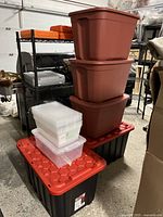 Eleven stacked storage bins including 2 large black and red Tuff Store bins and 3 solid merlot Type A bins with 6 clear Type A containers on top