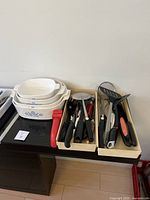 Top angle view showing stacked baking dishes next to trays of various kitchen utensils