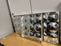 Three convex mirrors displayed leaning against a white wall, showing reflective domed surfaces in grid patterns.