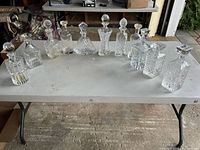 Photo showing a full lineup of 10 assorted crystal decanters on a table