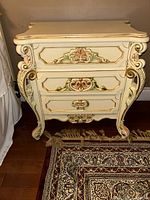 Front view of the ornate painted bedroom nightstand with 3 drawers and decorative carvings.