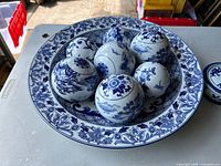 Large blue and white Bombay bowl containing seven decorative blue and white ceramic balls with floral and nature motifs