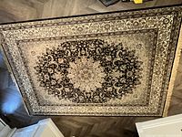 Full view of the carpet showing its overall black and creme floral pattern with central oval medallion.