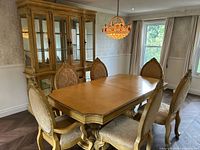 View of full dining room set including the table, six chairs around it, and glass-front hutch in background