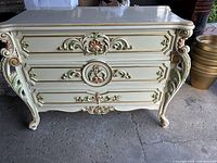 Front view of dresser showing three ornate drawers and carved details