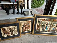 Four framed papyrus artworks featuring Egyptian scenes and hieroglyphics, framed in gold and dark wood finish.