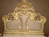 Full front view of the ornate queen size headboard showing carved details and padded upholstery.