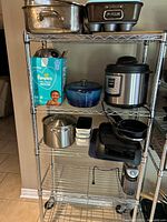 Metal shelving unit with stainless roaster, loaf pan, glass casserole and pressure cooker