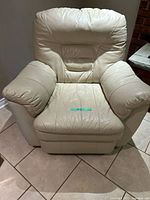Front view of one cream leather recliner chair showing padded arms, back and seat.