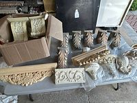 Overall lot of decorative wall brackets and corbels displayed on a table showing variety in size, color, and design.
