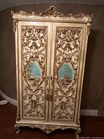Front view of full armoire showing carved doors and painted panels