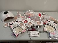 Wide view of all items including UV nail lamp and many packs of false nails scattered on table