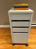 Front view of white office drawer cabinet with three drawers and colorful file divider on top.