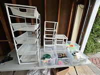 Full view of all storage items including metal frame drawer unit, plastic drawer organizer, and two clear plastic bins containing office supplies on a table.