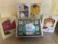 Photo showing all boxed American Girl Bitty Baby accessory items including tea party set, multiple outfits and grooming set.