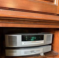 Front view of silver Bose Wave Music System stacked atop matching CD changer showing green LED tuner display (98.5).