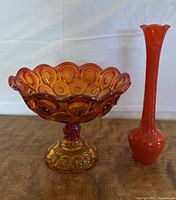 Photo of large scalloped glass compote bowl and tall slender bud vase both in amberina glass.