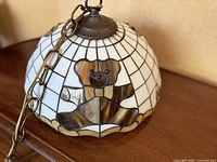 Close-up of stained glass bear motif on hanging lamp shade with metal chain attachment.
