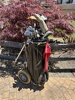 Full view of the black vintage golf bag standing with clubs inside, red towel attached