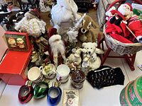Full view of the vintage Christmas lot showing multiple Santa figurines, stuffed animals, Christmas mugs, and holiday ornaments.