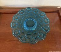 Top view of blue glass cake plate showing moon and star embossed pattern and scalloped edges.